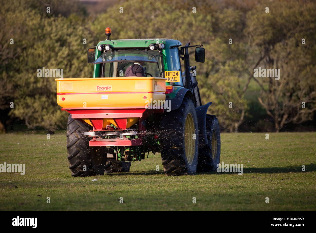 Green Farm tractor spreading fertilizer on field, Farming in