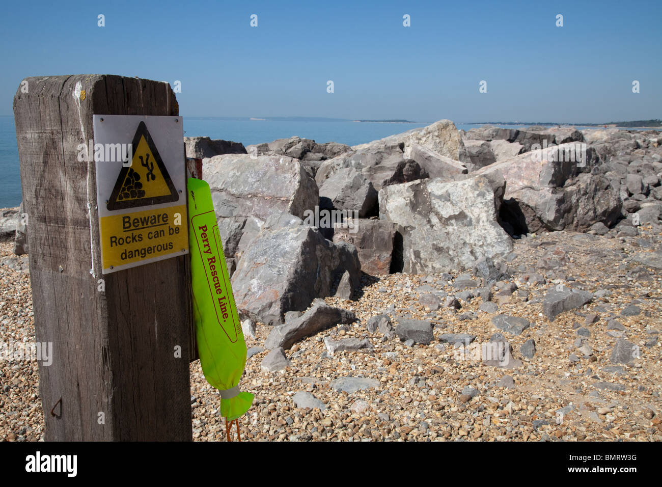 rescue line on post at seaside by dangerous rocks sign Stock Photo