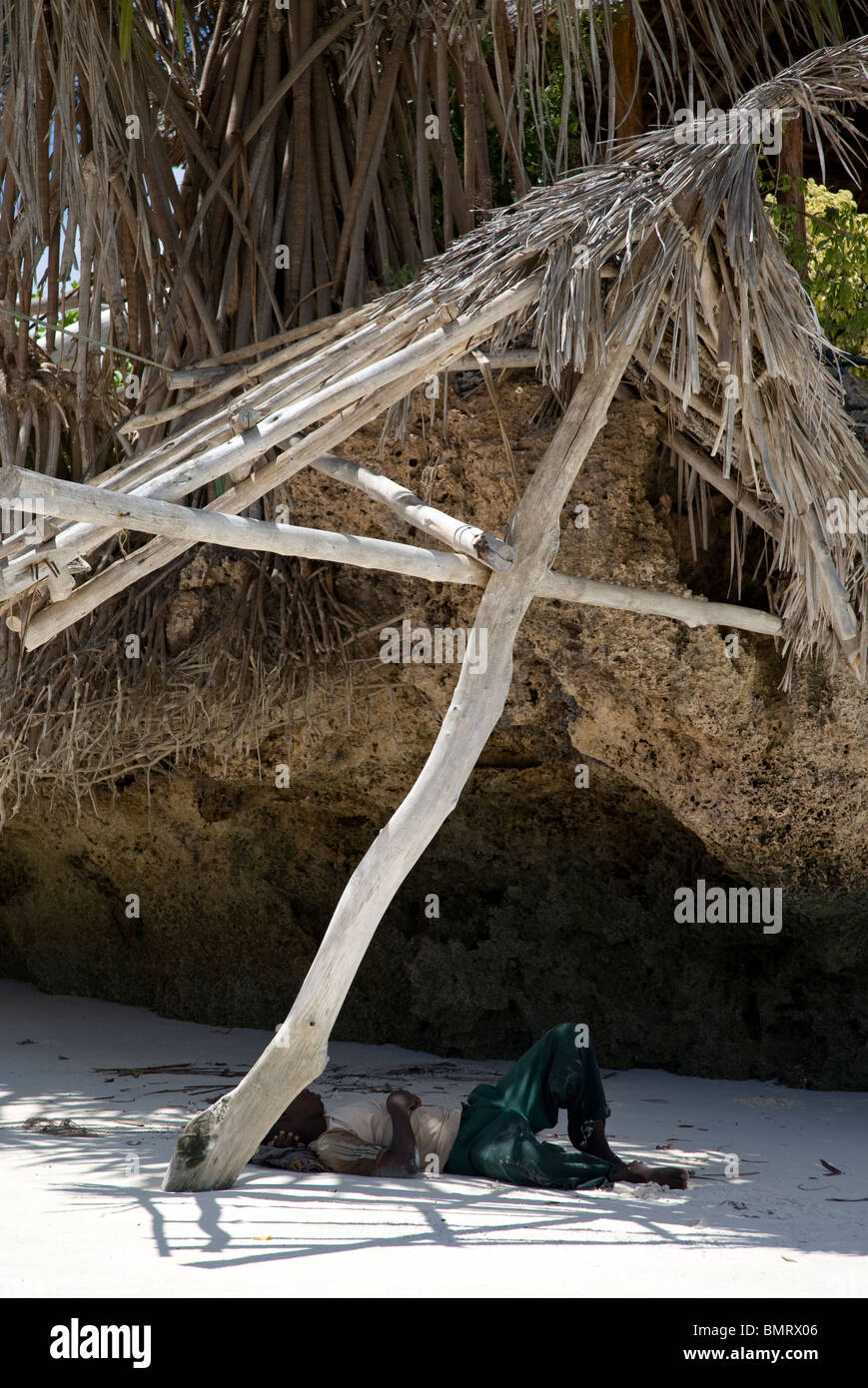 swahili man resting under a hut on the beach during his lunch break in