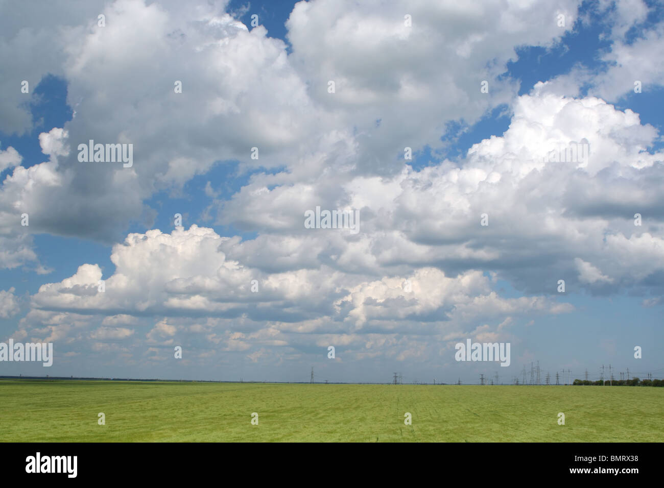 Green field under blue cloudy sky Stock Photo - Alamy