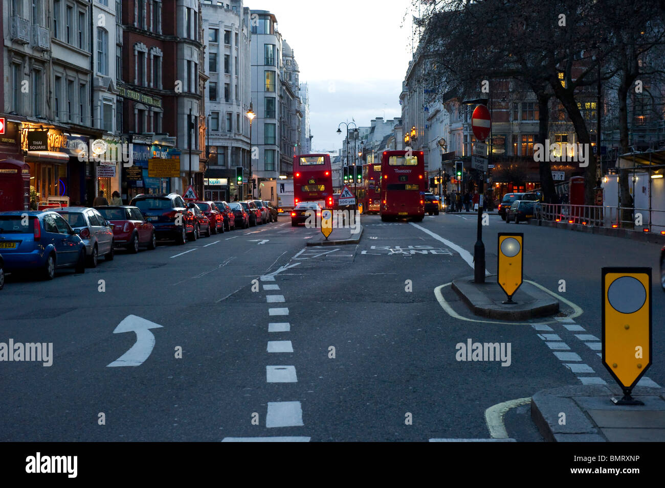 Famous red London buses travel along The Strand towards Trafalgar Square. Stock Photo