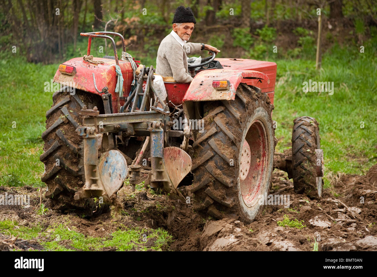 Senior farmer using an old tractor to plow his land Stock Photo