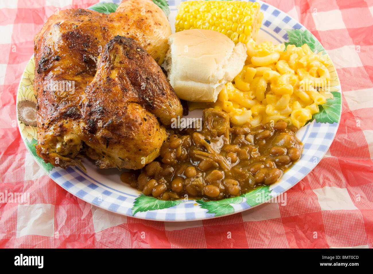 picnic style BBQ chicken plate with half smoked chicken, baked beans, macaroni, roll, corn on the cob Stock Photo
