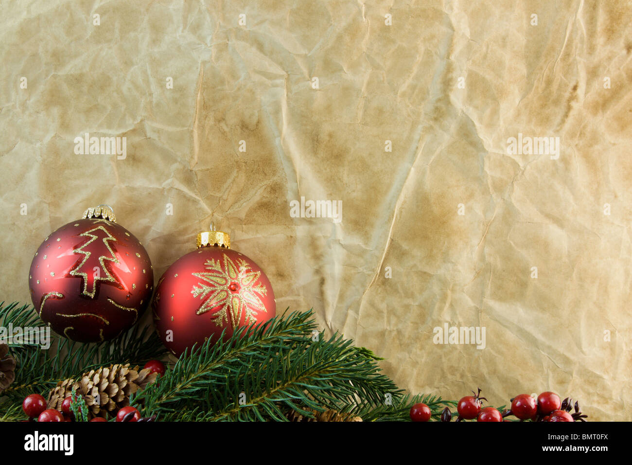 two red Christmas ornaments, fir branch with old fashioned antique paper background and copyspace Stock Photo