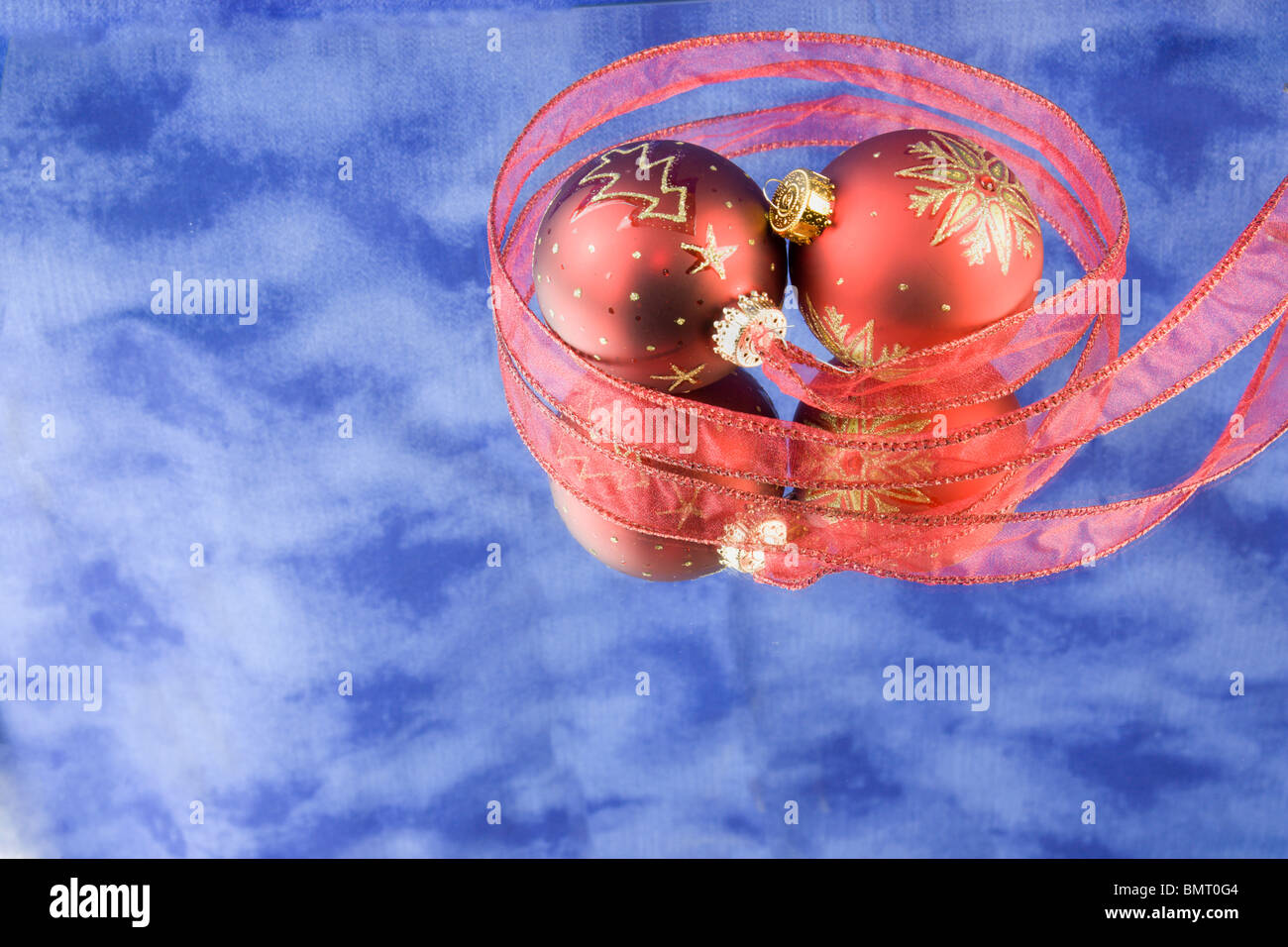 two Christmas baubles with wide red ribbon, blue background, reflections, and copyspace Stock Photo