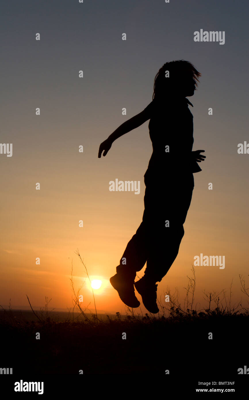 jump of little girl in sunset - silhouette Stock Photo