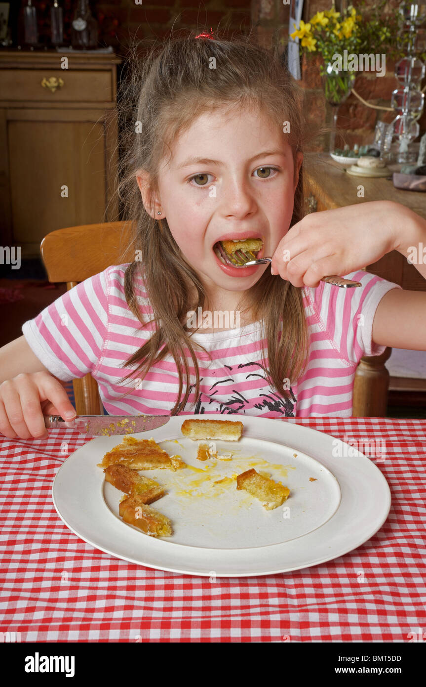 Young girl eating fried bread dipped in egg for breakfast Stock Photo