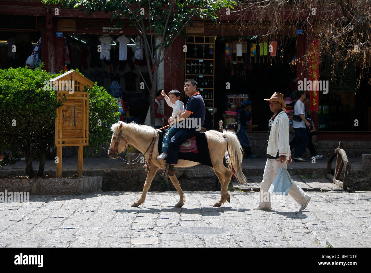 Father and son on horseback Sifong Square Lijiang Old Town Yunnan China Stock Photo