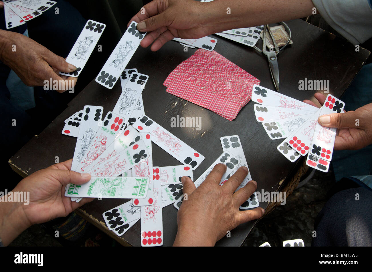 Close-up hands playing chinese card game Sifong Square Lijiang Old Town Yunnan China Stock Photo