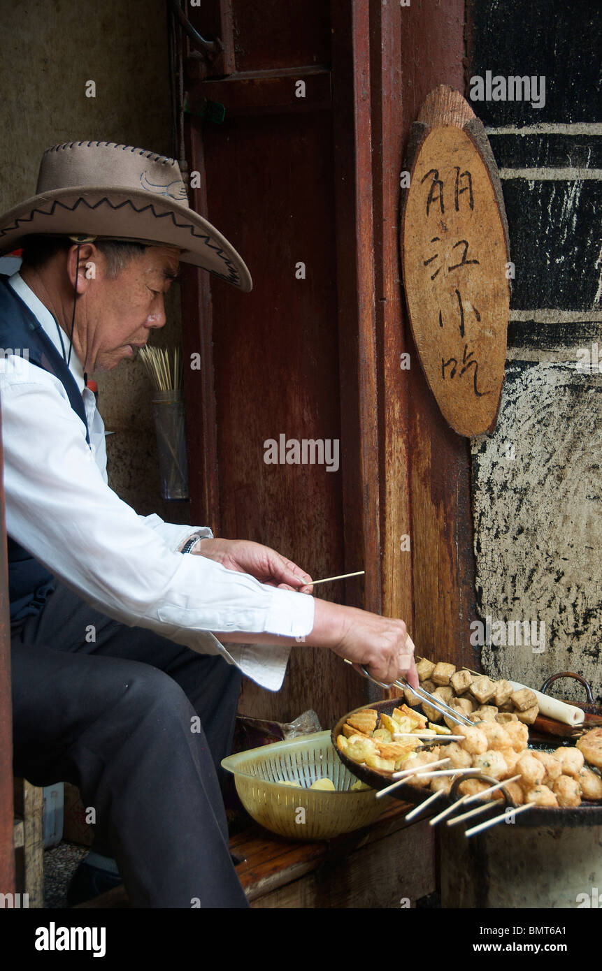 Man frying food in doorway Lijiang Old Town Yunnan China Stock Photo