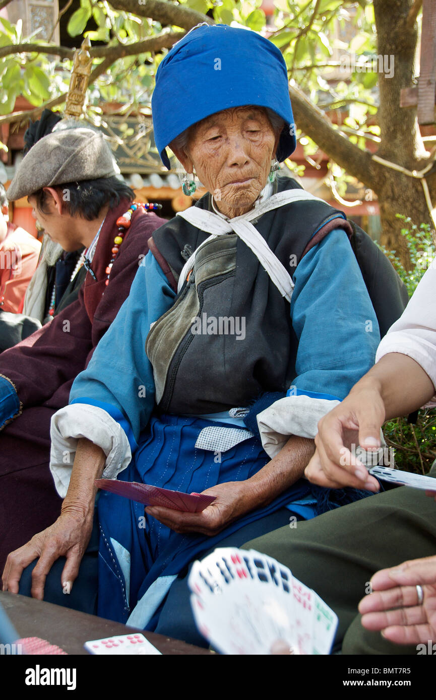 Old Naxi woman playing chinese card game Sifong Square Lijiang Old Town Yunnan China Stock Photo