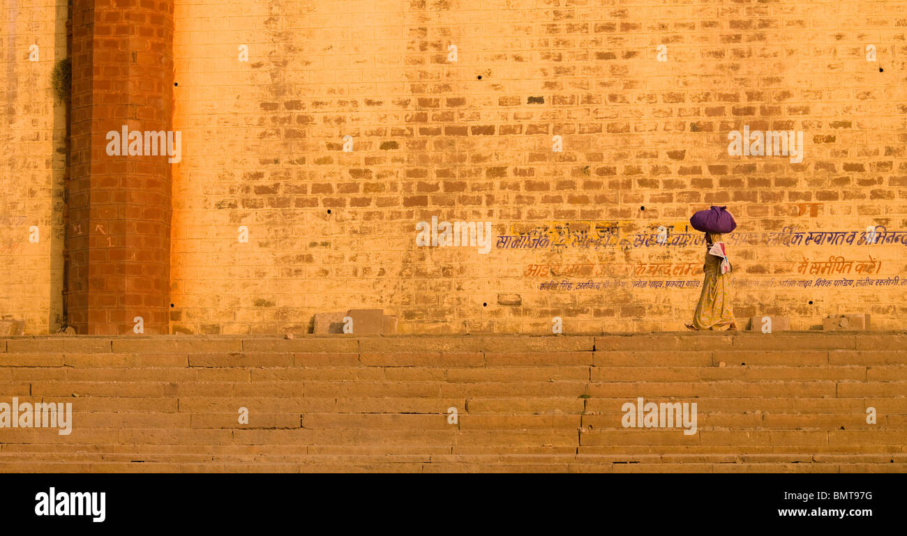 The Ganges,Varanasi,India;Woman Carrying Bundle On Her Head On The Ghats By The River Stock Photo