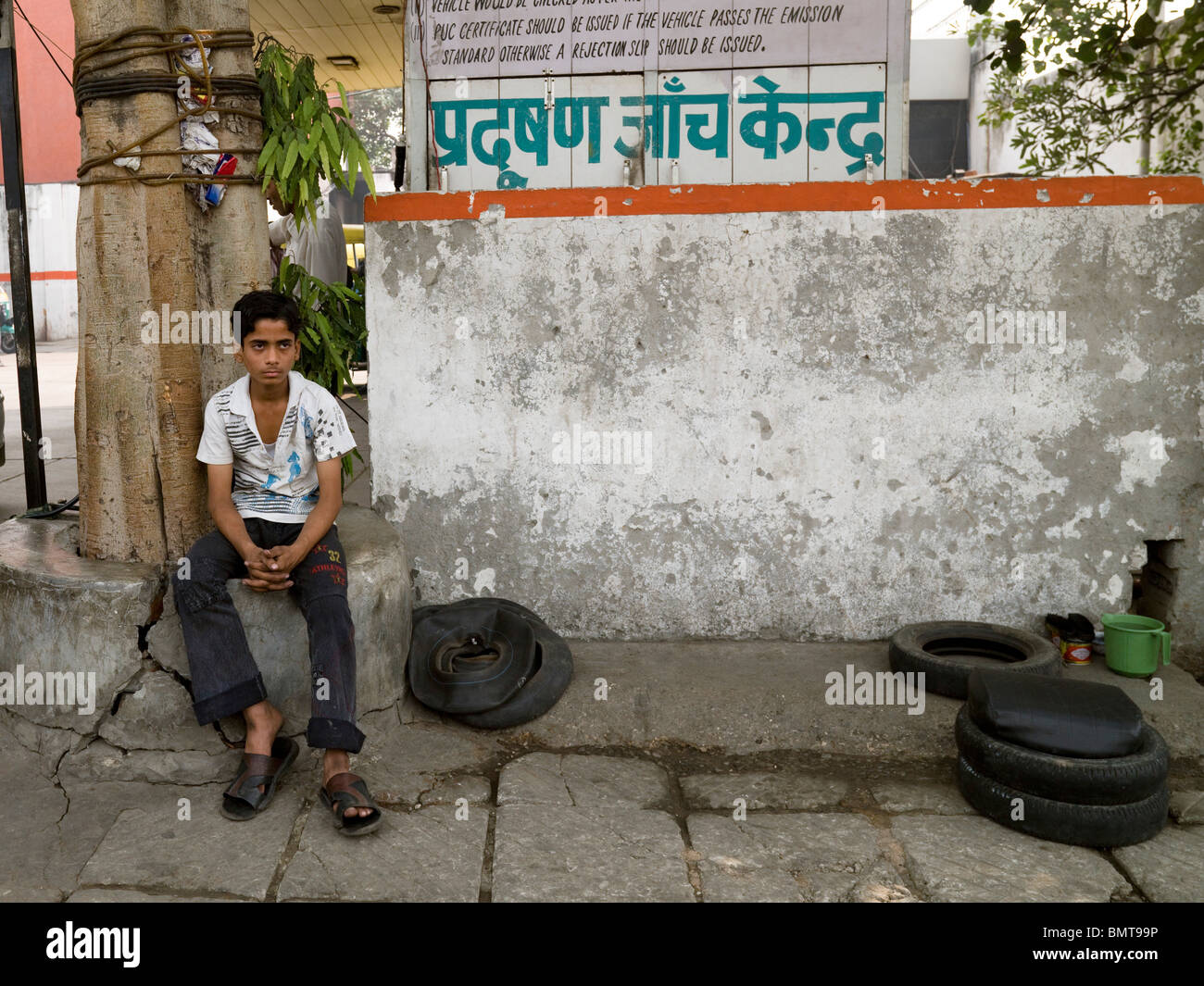 Delhi,India;Portrait Of A Boy Sitting Outside Car Mechanics Stock Photo