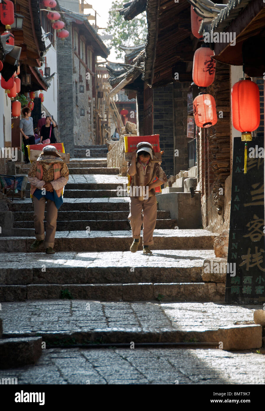 Man and woman carrying loads Lijiang Old Town Yunnan China Stock Photo