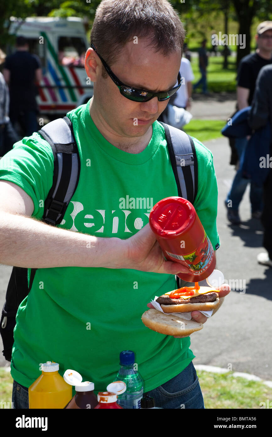 Man putting tomato sauce onto a hamburger, West End Festival, Glasgow, Scotland, UK, Great Britain Stock Photo