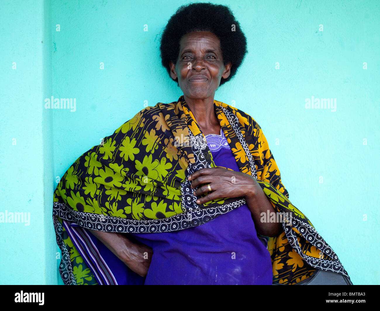 Black lady in blue wearing a green and yellow flowery blanket in Rwanda post genocide Stock Photo