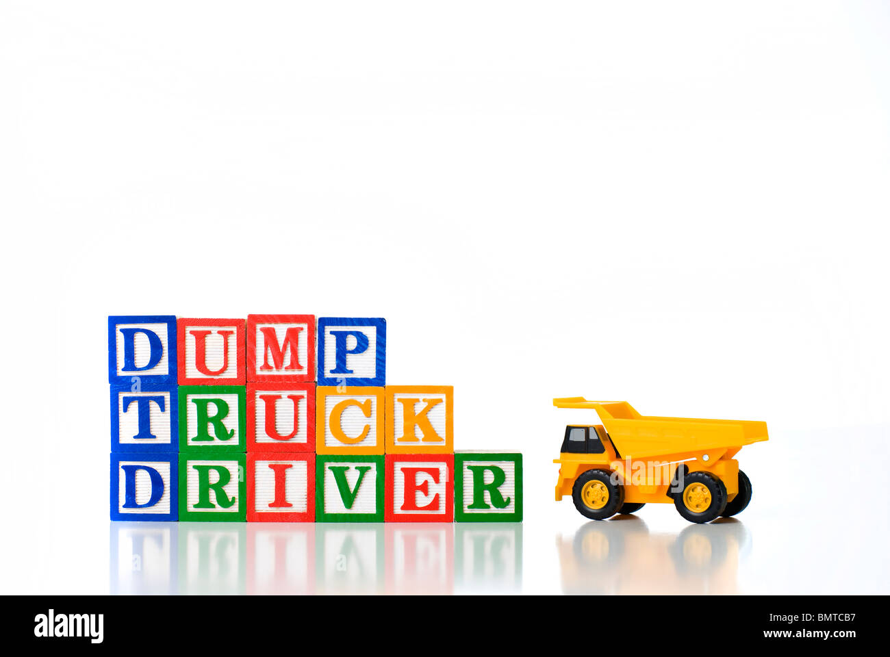 Colorful children's blocks spelling DUMP TRUCK DRIVER with model dump truck Stock Photo