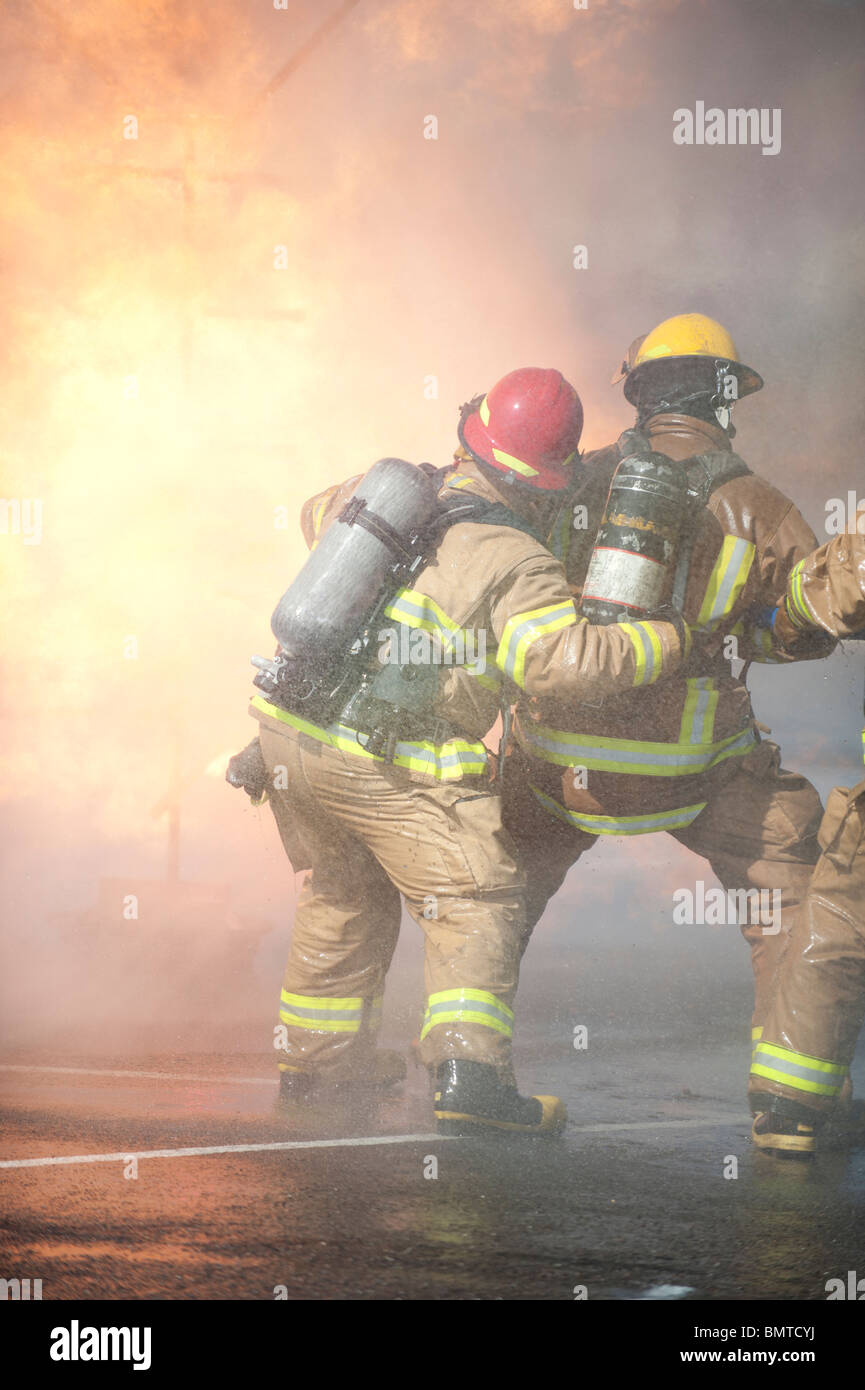 Directed by an officer in a red helmet, firefighters attack a propane ...