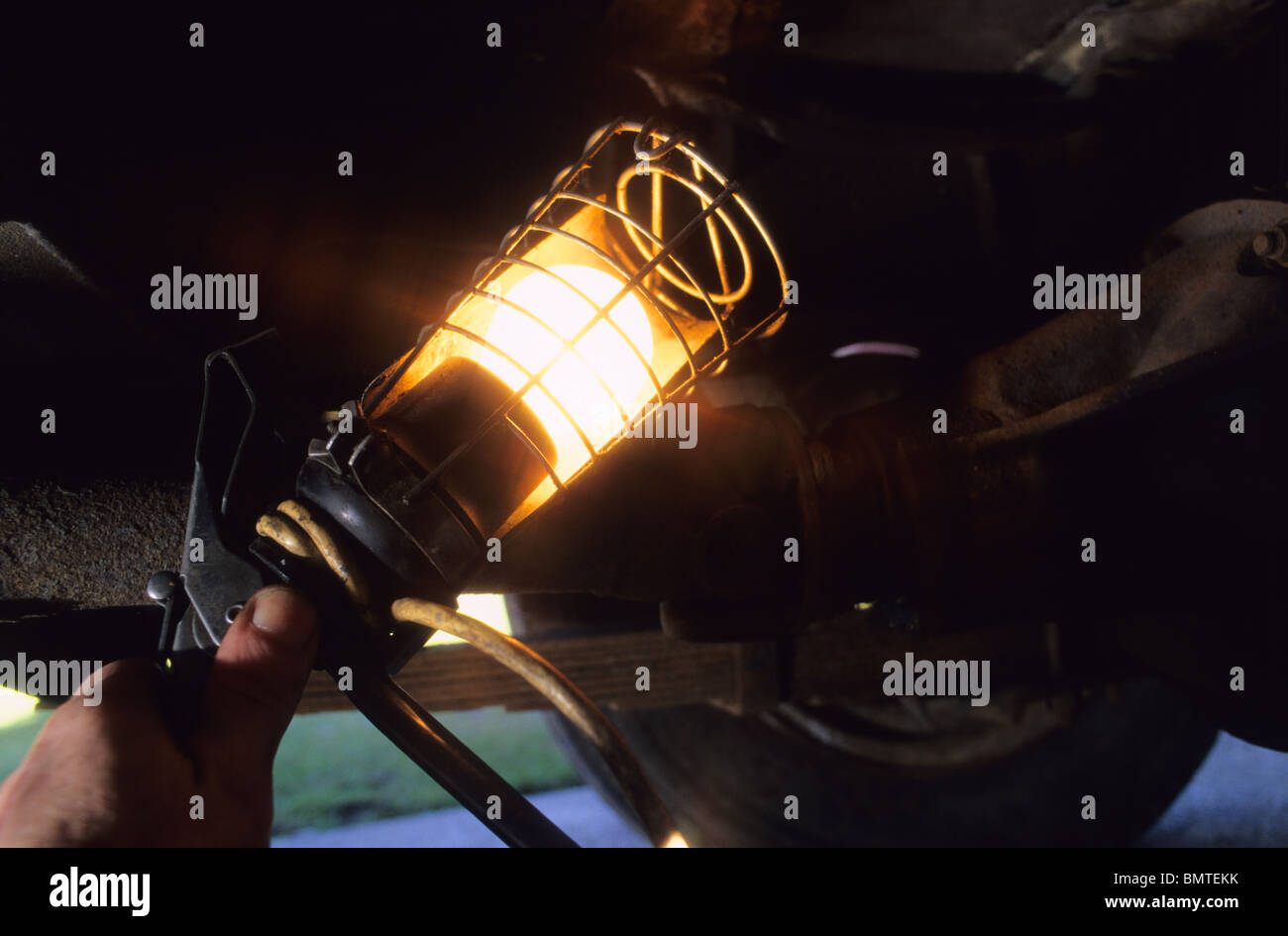 mechanic working underneath vehicle using inspection lamp Stock Photo