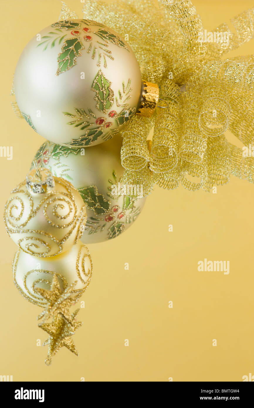 gold holly leaf Christmas bauble with gold bow, swirl bauble, star on a gold background with copyspace Stock Photo