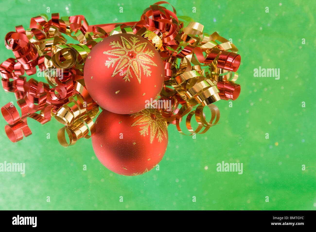 red Christmas bauble with gold snowflake, red and gold curly ribbon, soft green background and copyspace Stock Photo