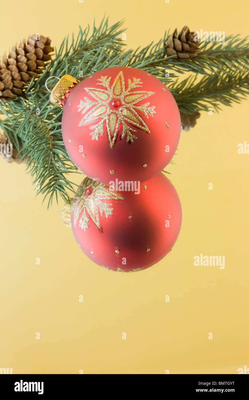 red Christmas snowflake bauble with fir branch, reflections on a gold background and copyspace Stock Photo