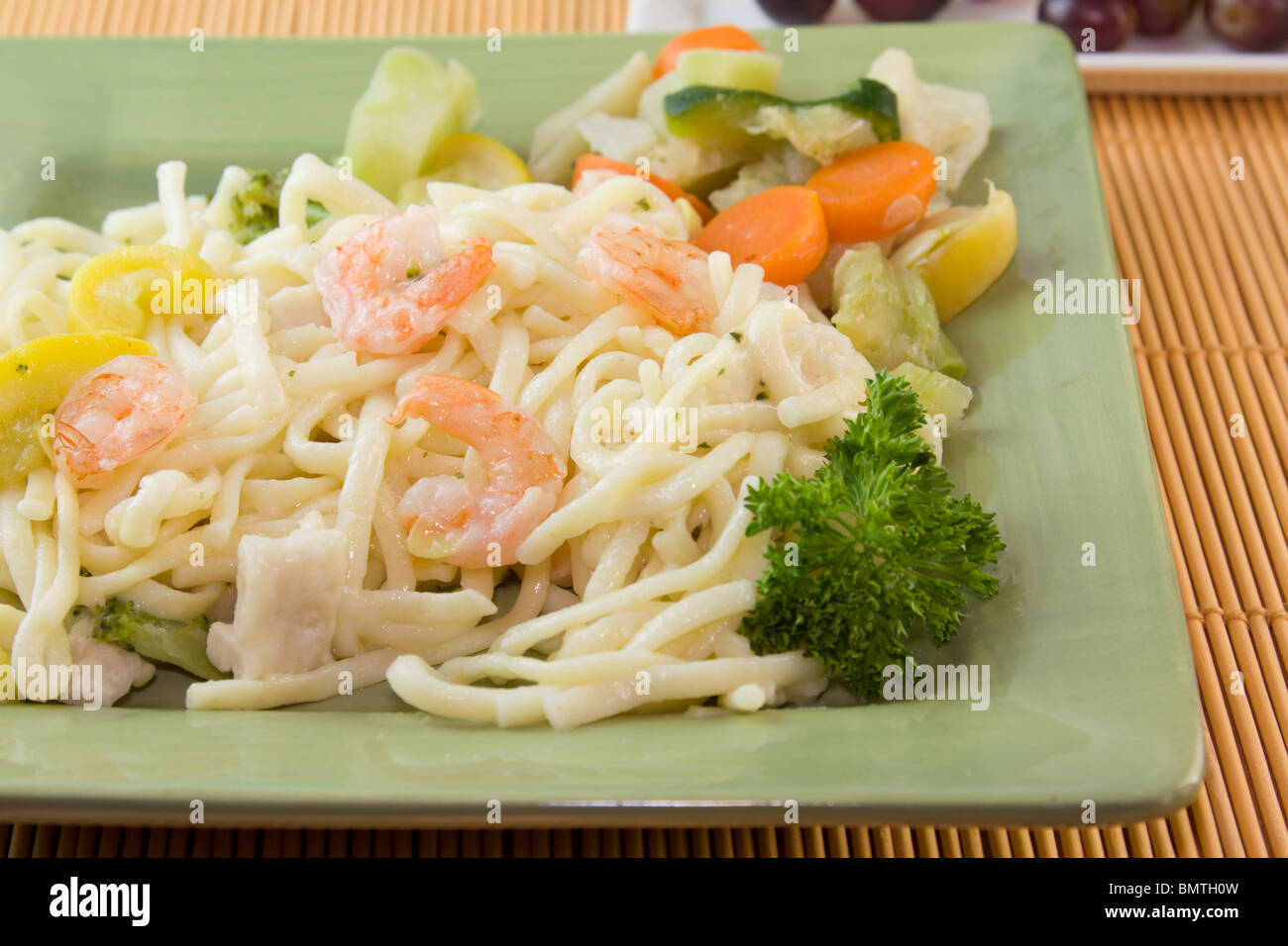 closeup of shrimp alfredo pasta with sliced squash and carrots Stock Photo