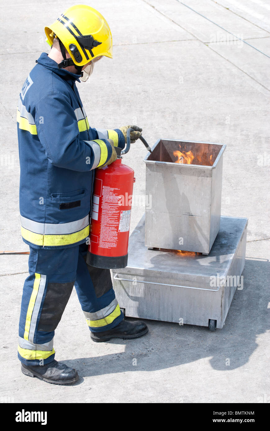 Firefighter putting out controlled fire using extinguisher Stock Photo Alamy