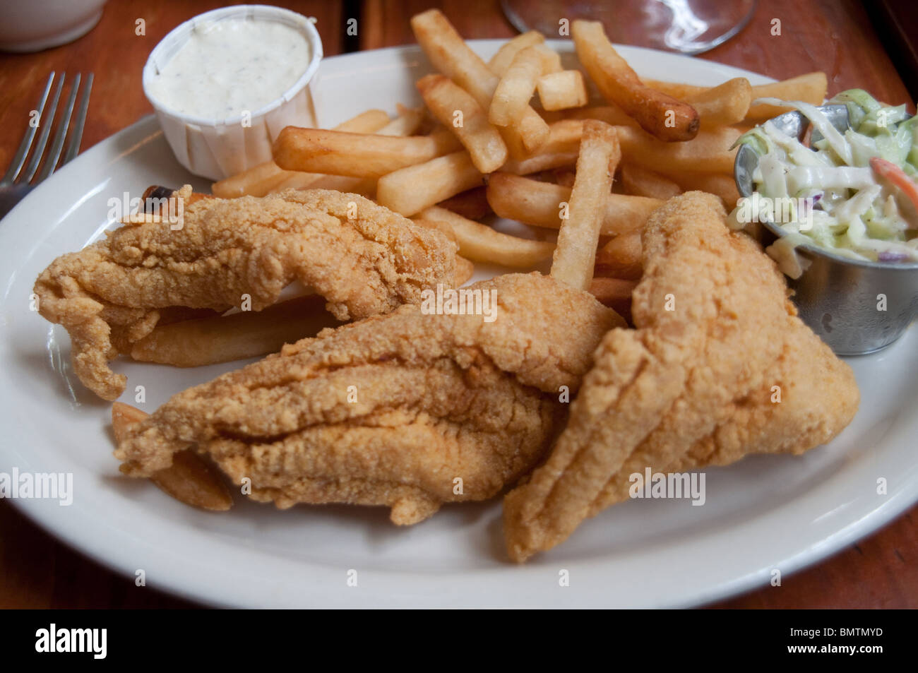 Deep fried catfish served with fries, coleslaw and tartar sauce at a roadhouse cajun and creole restaurant in Shreveport, Louisiana, United States. Stock Photo