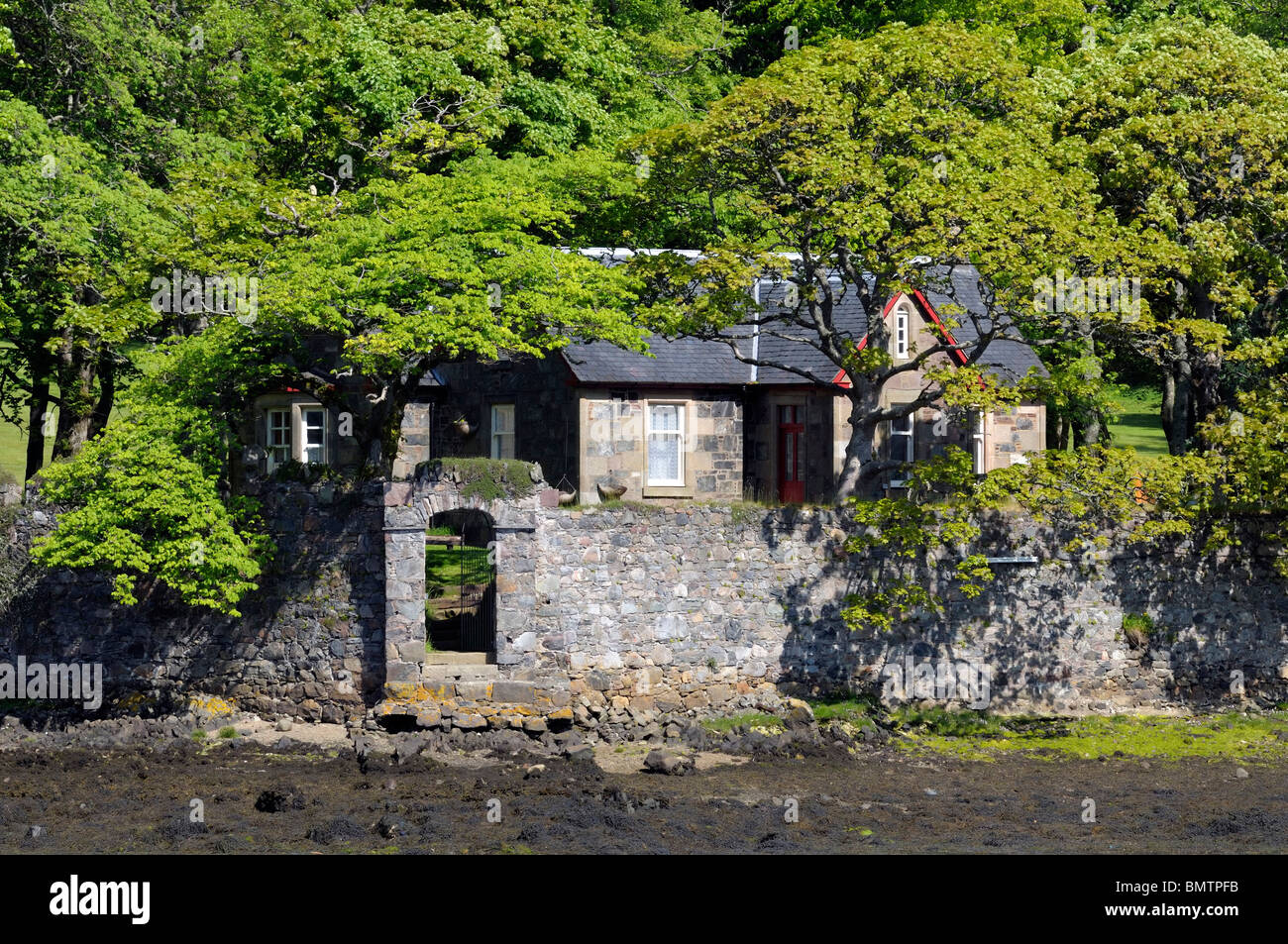 Secluded small house with a walled garden set in woodland on an river estuary. Stock Photo