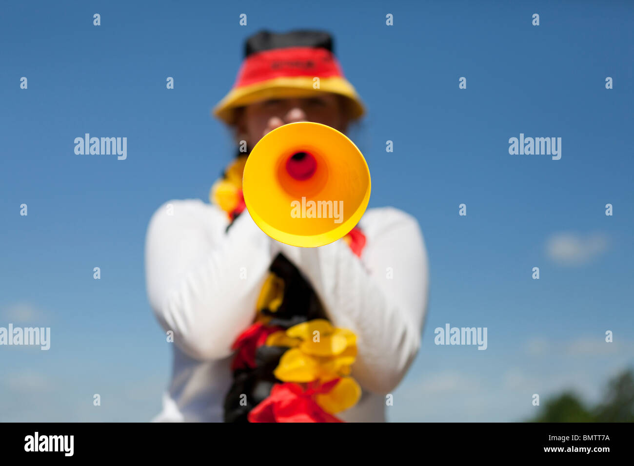 Female soccer fan blows vuvuzela Stock Photo