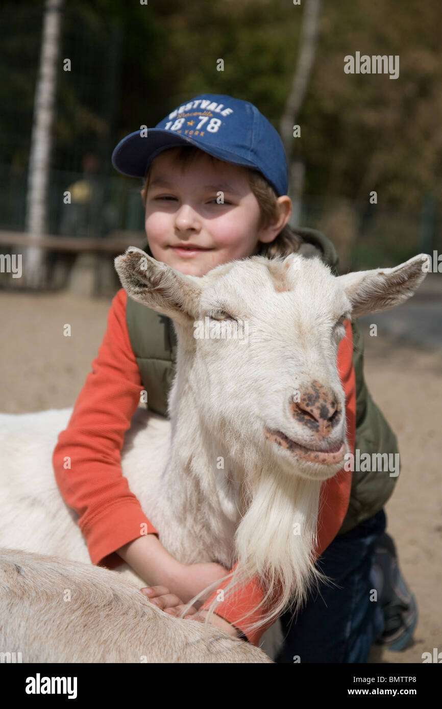 Boy hugging a goat on a platform for young Stock Photo Alamy