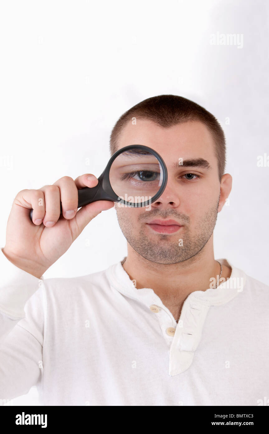 Young man putting a magnifying glass on one eye Stock Photo