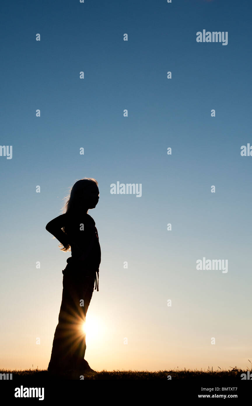 Solitary Young Girl standing against a sunset. Silhouette Stock Photo ...
