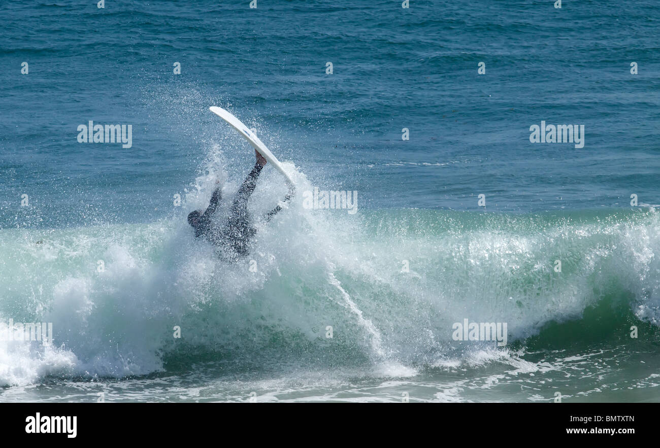 Surfer falls from his surf board after being hit by a wave Stock Photo
