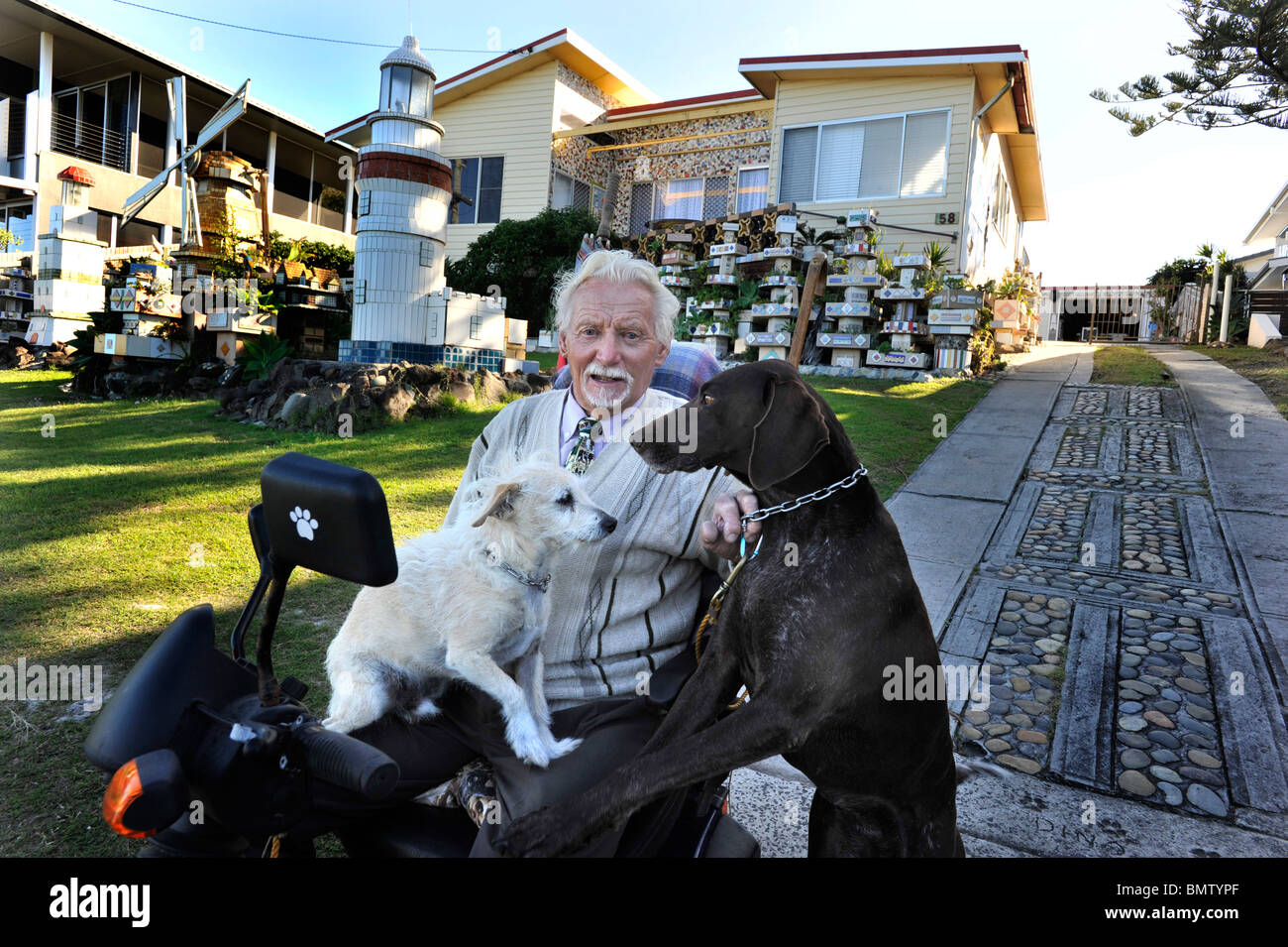 Peter with his friends Rufus (L) and Gypsy in front of his unique tiled home at Shelley beach Ballina Stock Photo
