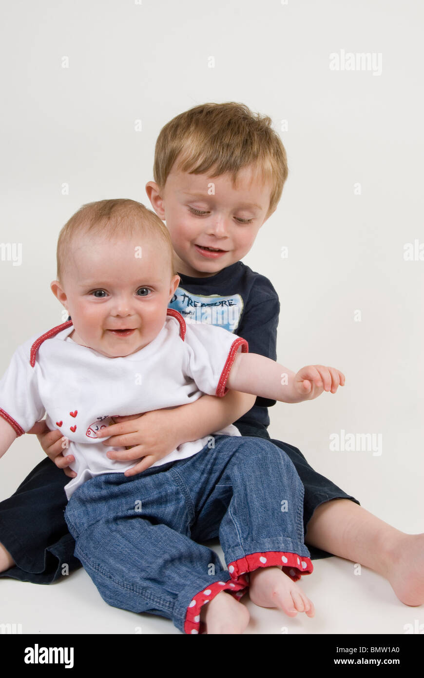 Portrait of Little Boy Holding Baby Sister, Isolated on White Stock