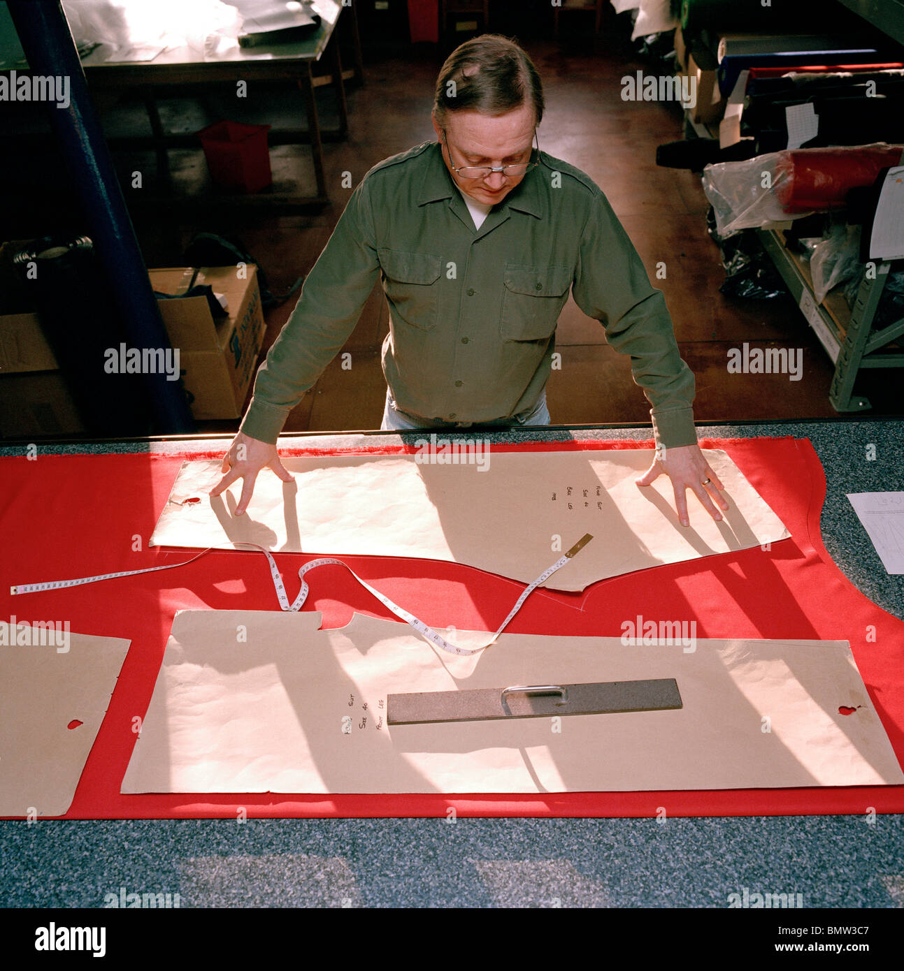 A tailor cuts red material for flying suits of the elite 'Red Arrows', Britain's prestigious Royal Air Force aerobatic team. Stock Photo