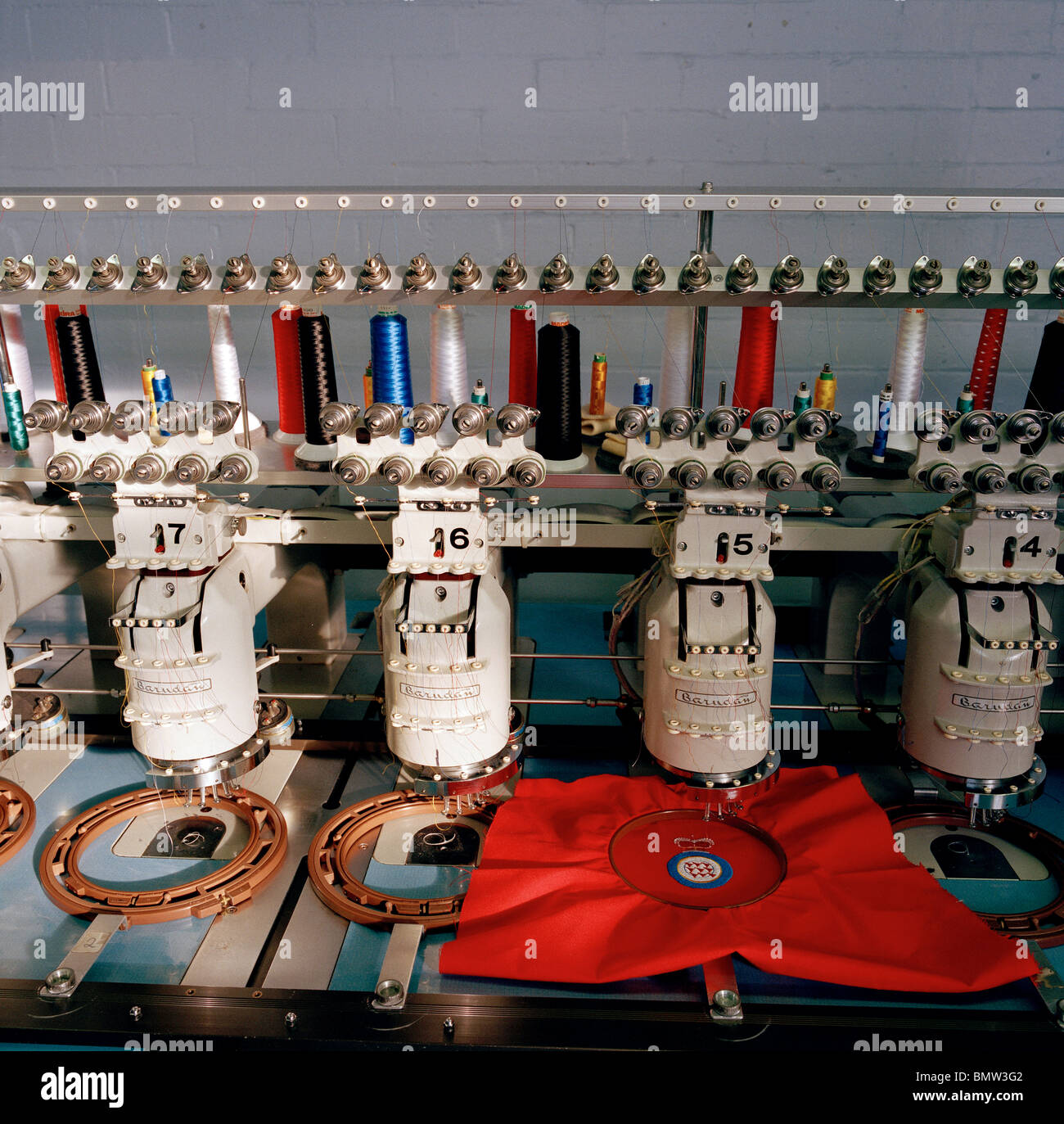 Automated stitching machine works on badges for the elite 'Red Arrows', Britain's prestigious Royal Air Force aerobatic team. Stock Photo