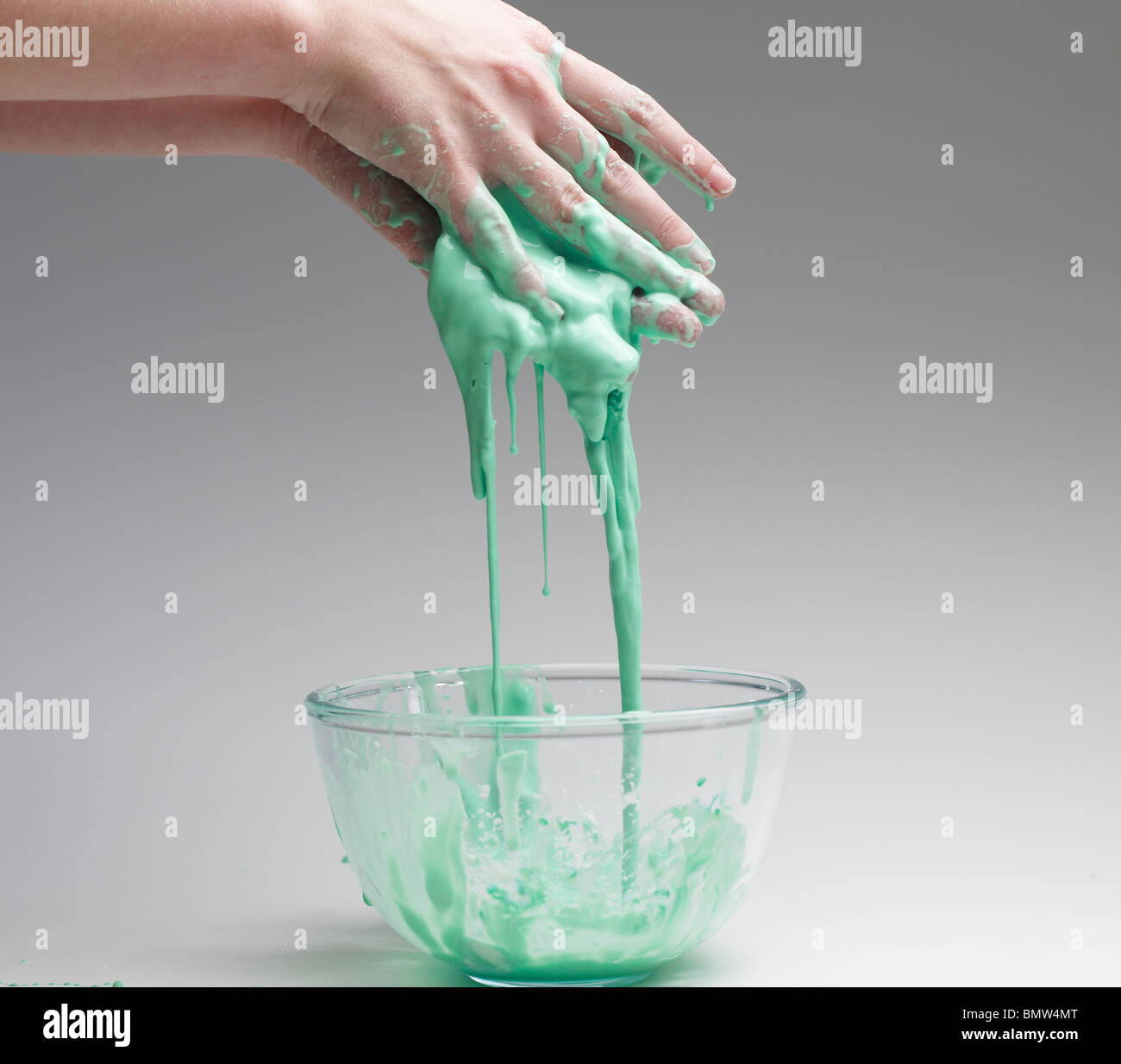 Green slime running off hands into a bowl Stock Photo