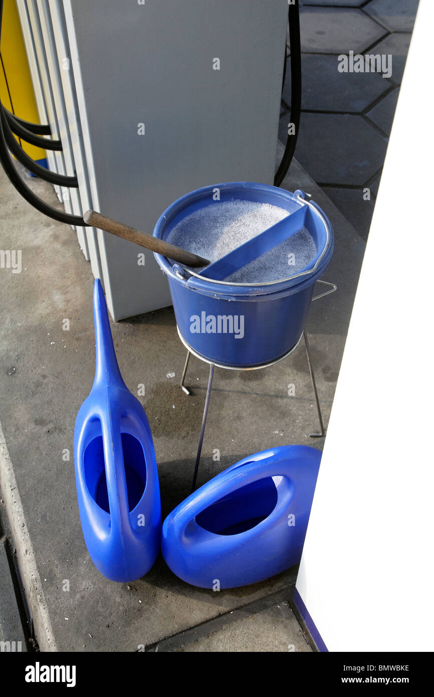 A bucket and water cans at a petrol station Stock Photo