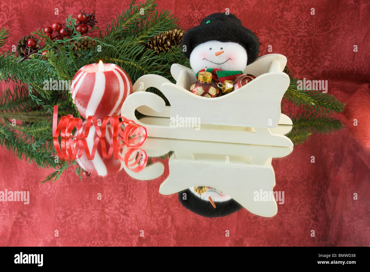 traditional Christmas snowman in sleigh with candle, ribbon, fir branch, reflections and copyspace Stock Photo