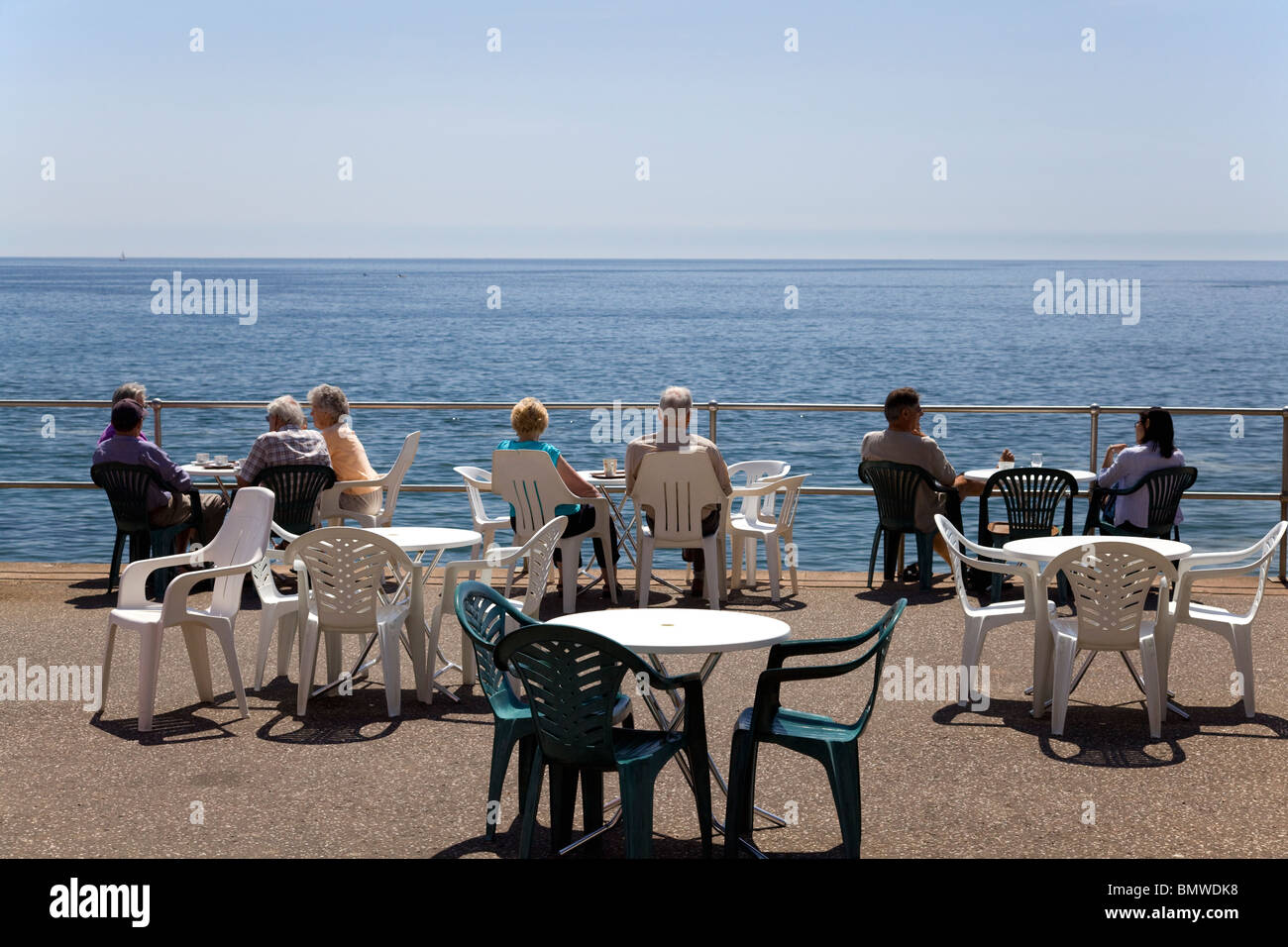 People sitting at café tables on the sea front at Seaton, Devon Stock Photo