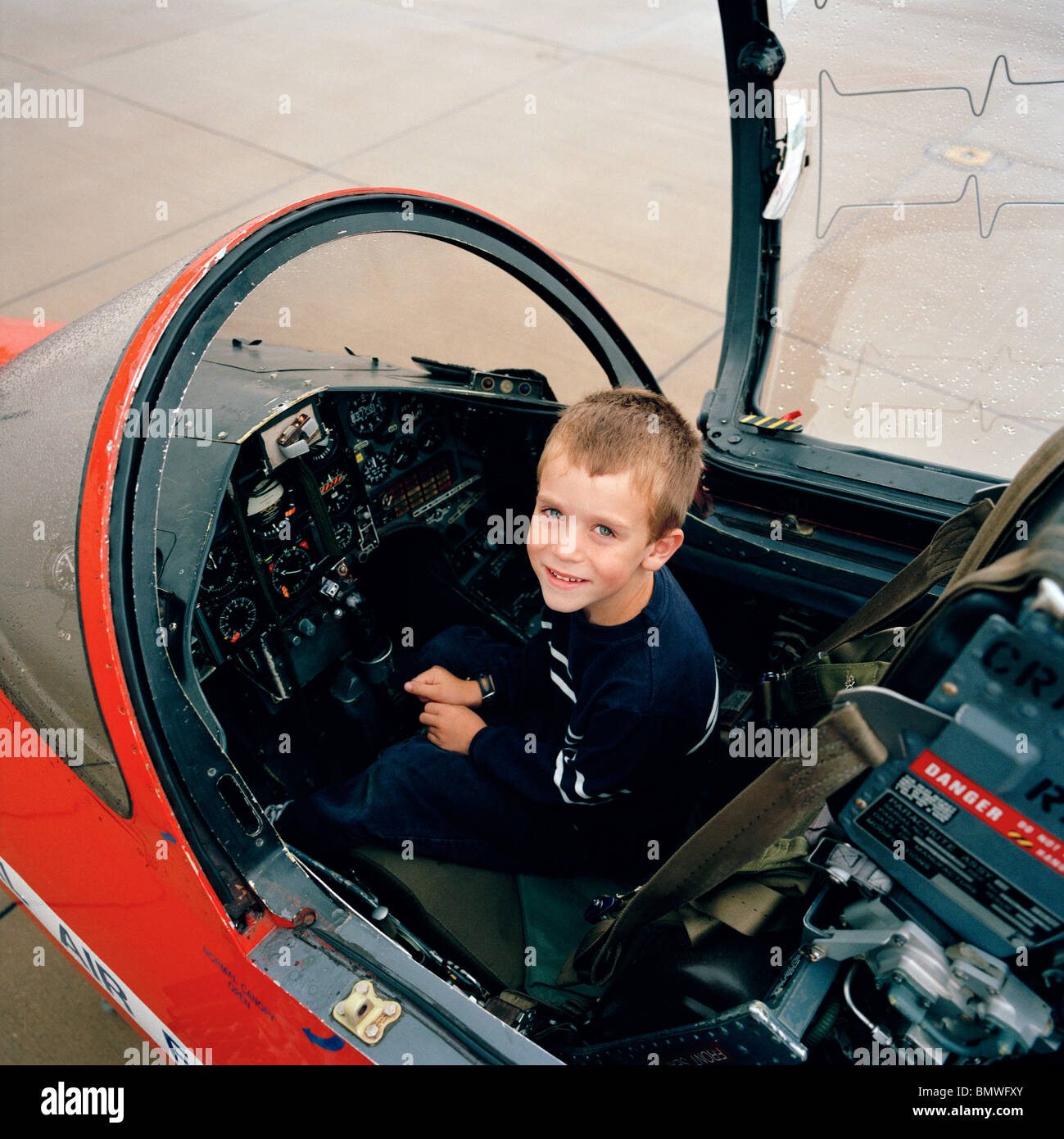 A young boy sits in BAE Systems Hawk cockpit of the 'Red Arrows', Britain's Royal Air Force aerobatic team. Stock Photo