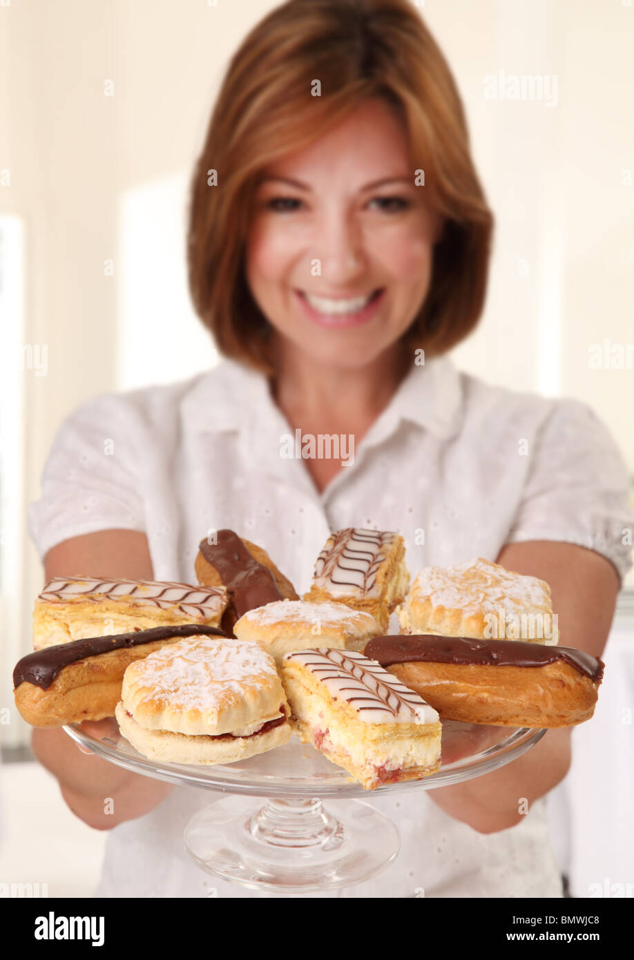 WOMAN HOLDING PLATE OF FRESH CREAM CAKES Stock Photo