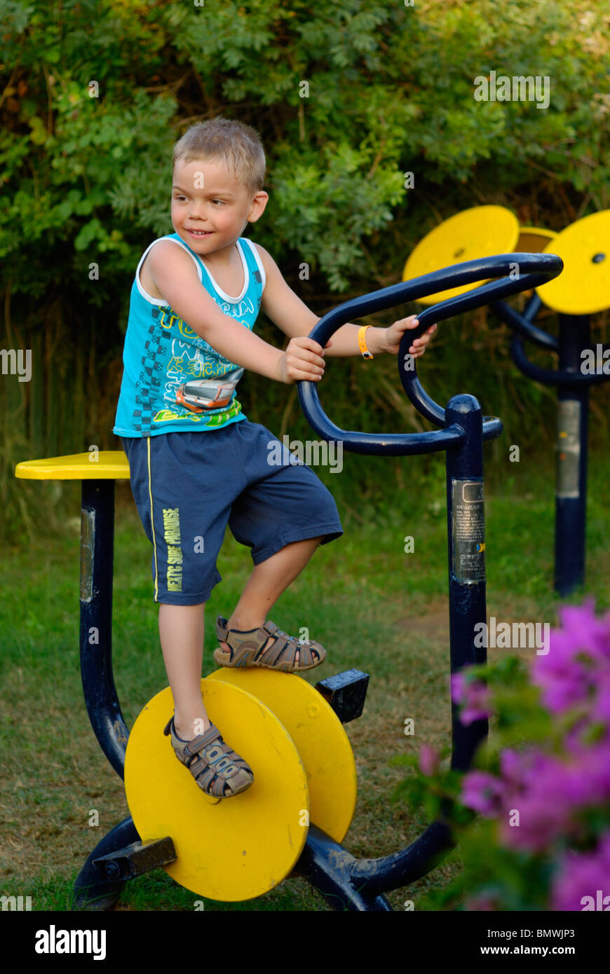 Little boy on the exercise bicycle at the sport ground Stock Photo