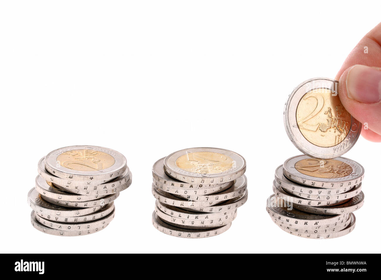 Hand puts a two-eur coin on third coin column isolated on white background Stock Photo