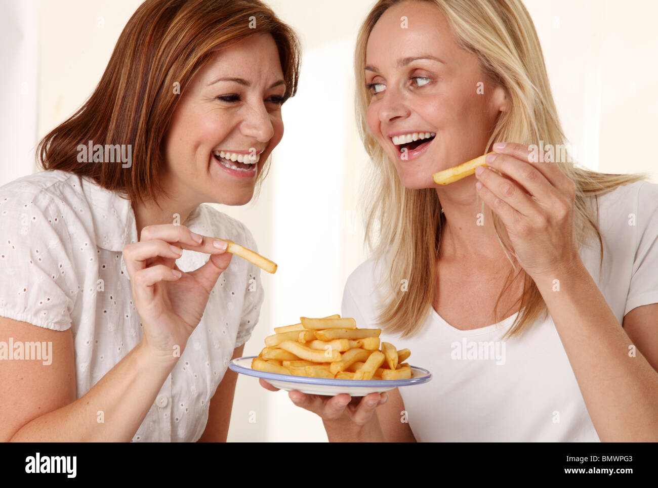 TWO WOMEN EATING FRENCH FRIES Stock Photo - Alamy