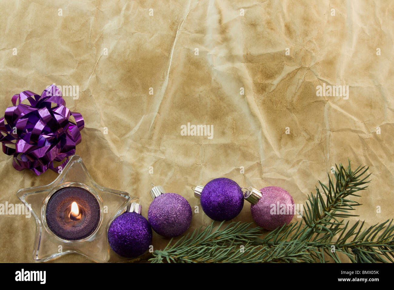 purple tealight in star holder, Christmas baubles on antique style paper with copyspace Stock Photo
