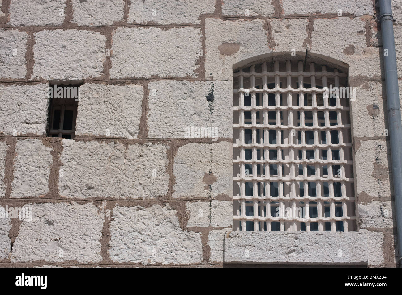 barred bars arch window stone wall peephole small Stock Photo